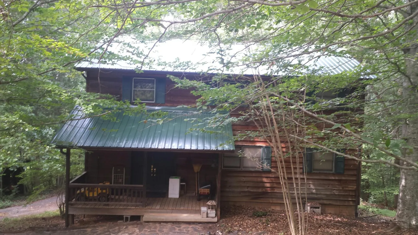 Green metal roof and covered porch on a log cabin in Lakeville